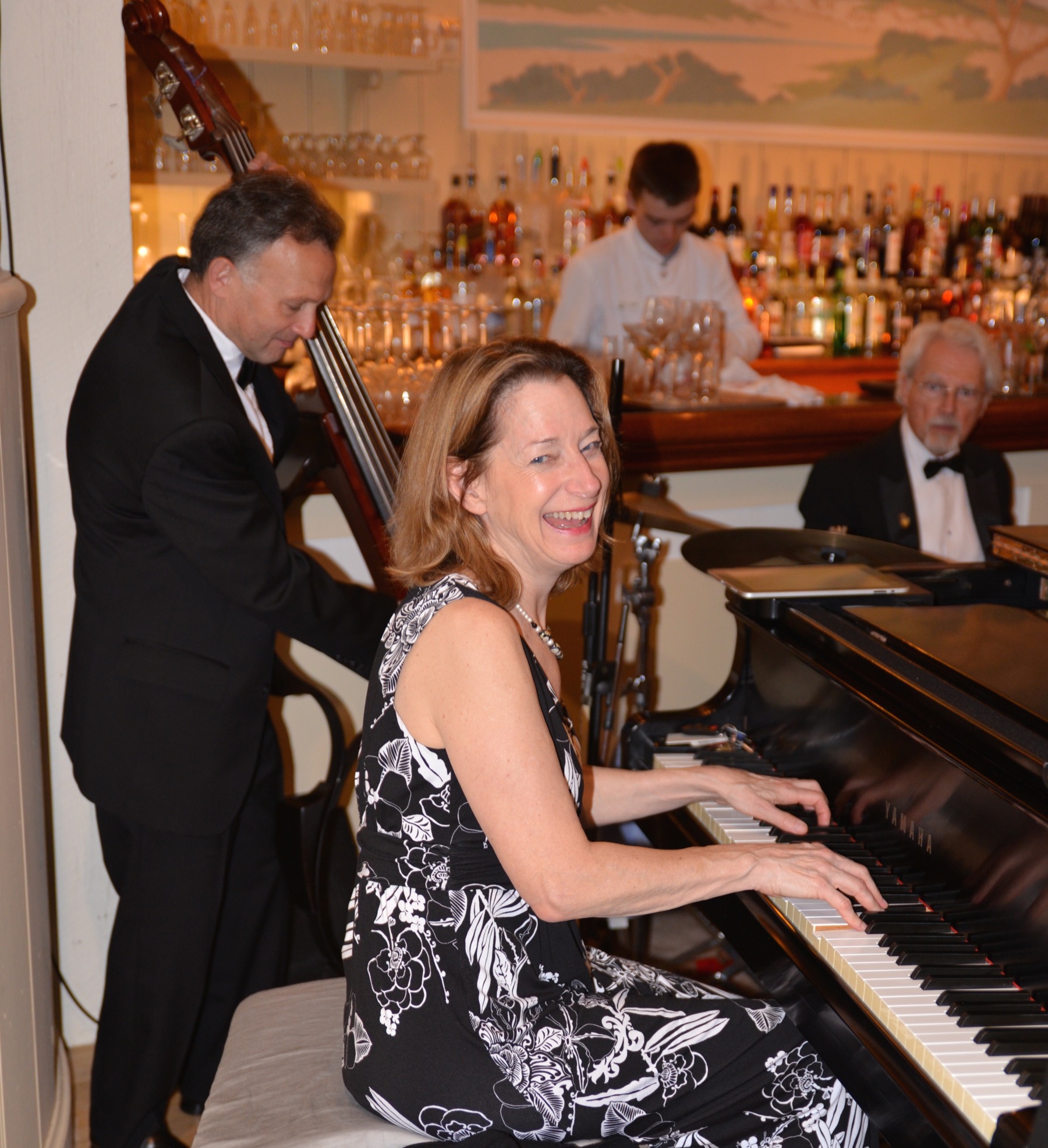 Debbie Sullivan performing at the piano with acoustic bass and drums